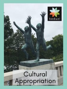 Statues by Gustav Vigeland in Oslo, Norway, of two young humans running scared. Over the image are the words, “Cultural Appropriation” and the Keduzi logo, which is a colourful flower.